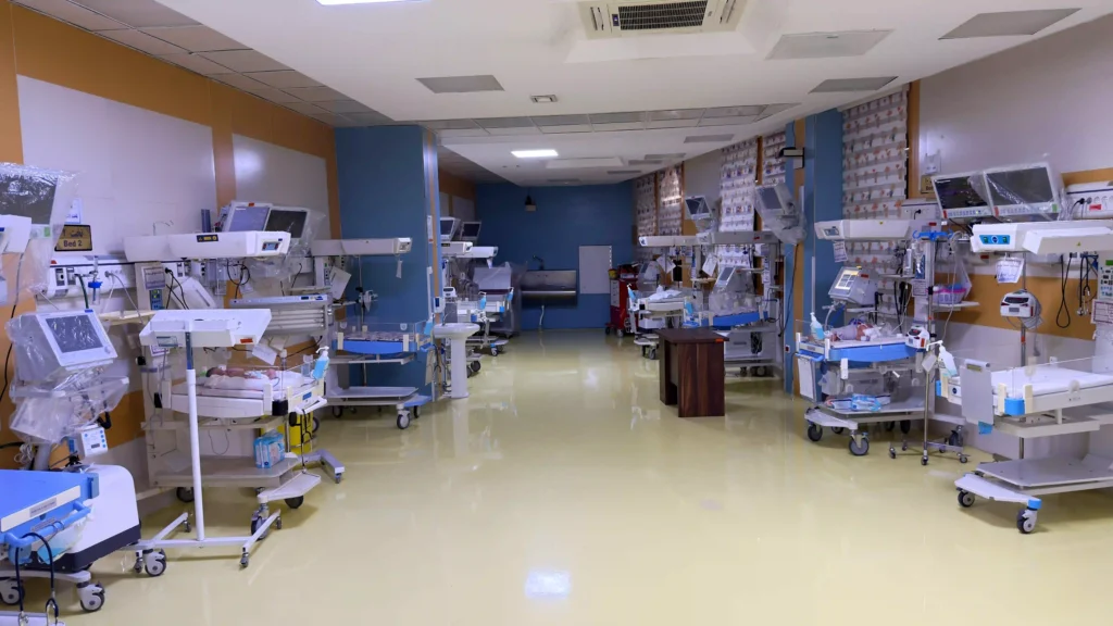 نوزادان در بخش مراقبت‌های ویژه (NICU) در تخت‌های مخصوص با مانیتورهای پزشکی متصل، تحت مراقبت پرستاران و پزشکان.